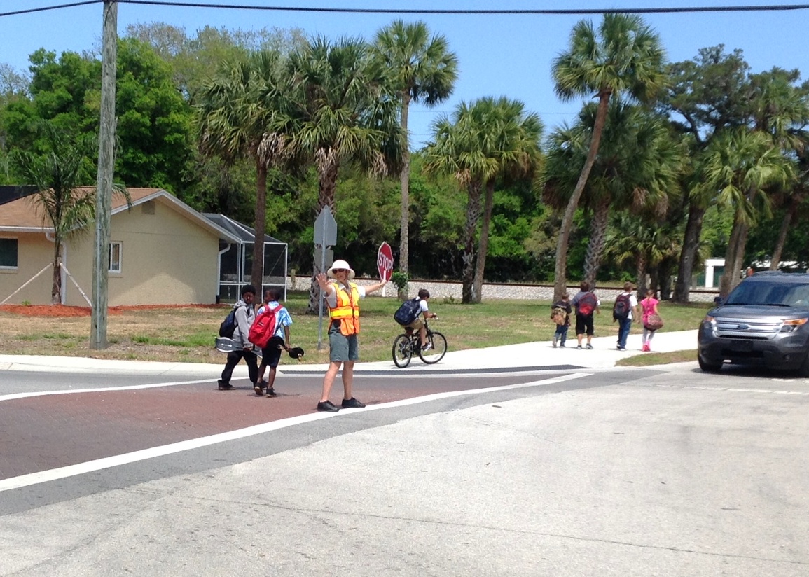 Corssing Guard stopping traffic for kids to cross the road